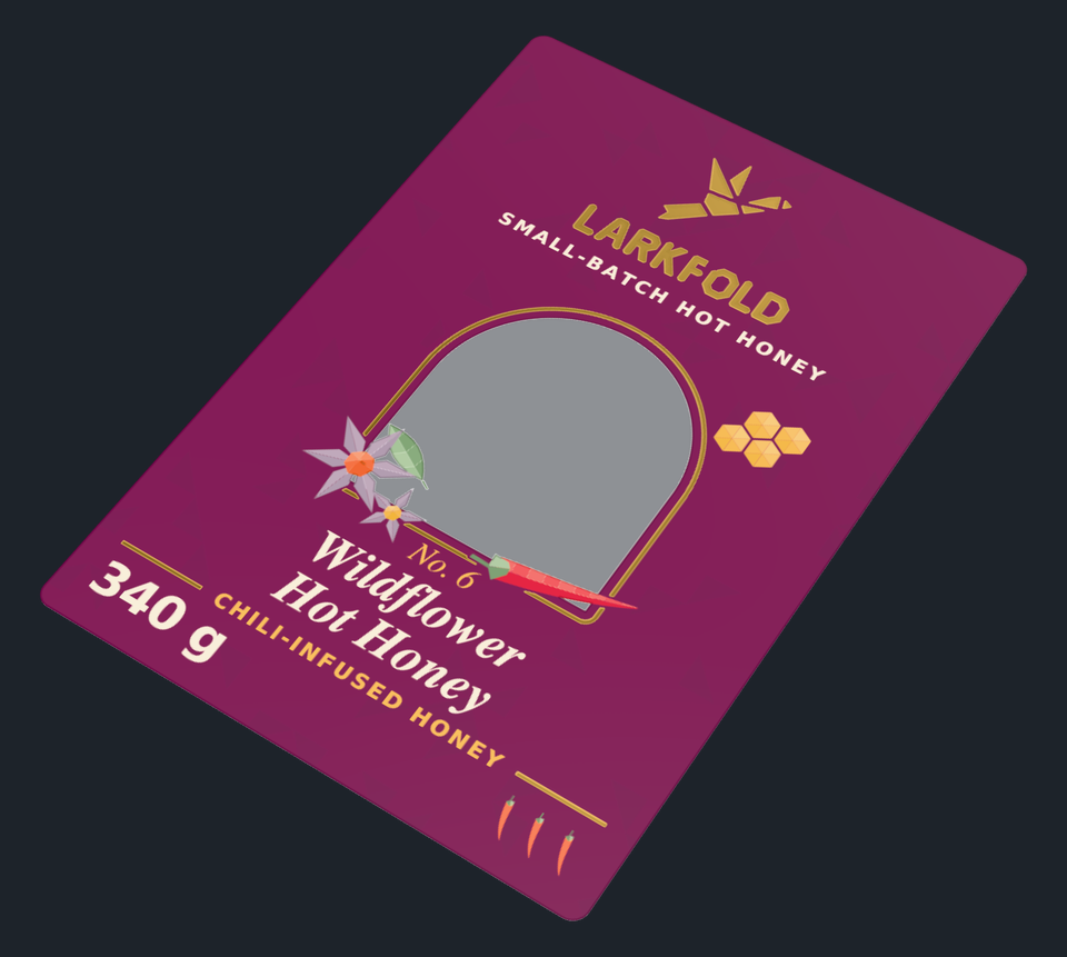 A clear bottle label lying flat on a dark backdrop, white ink and gold foil on clear film